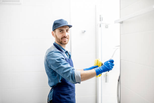 Professional cleaner wiping a glass shower door